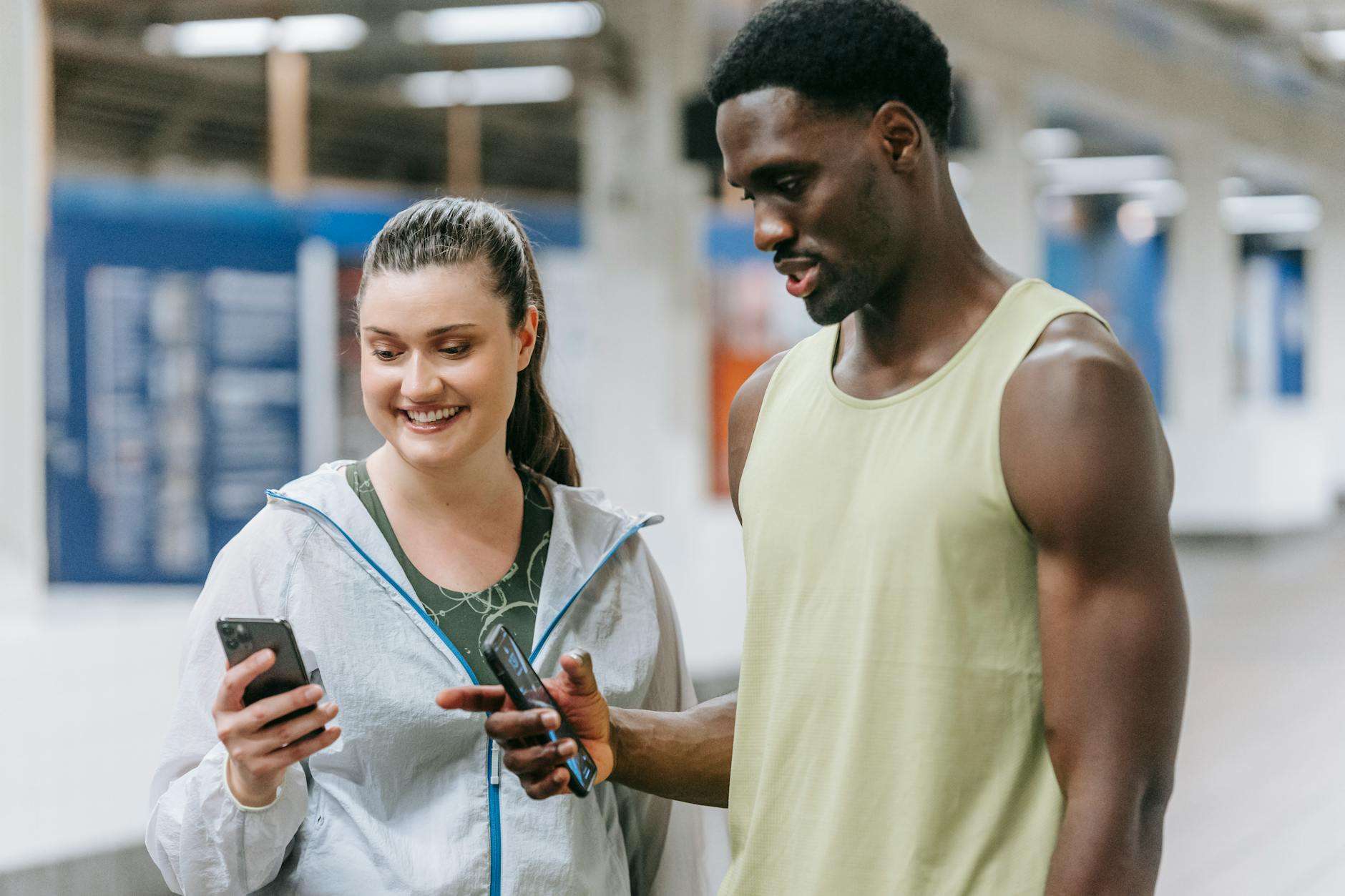 young man and woman in sports clothing looking at a smartphone screen