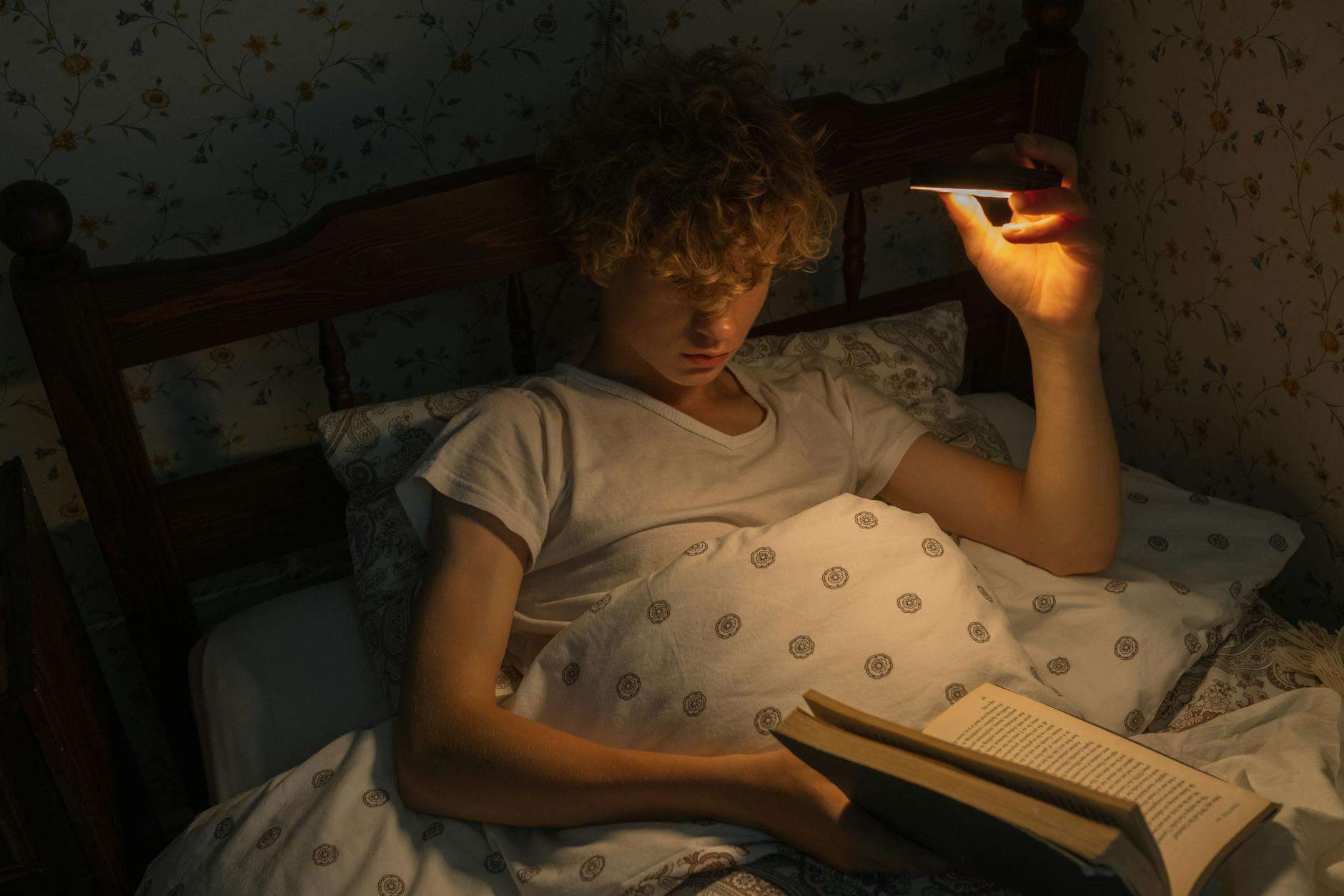 https://www.pexels.com/photo/teenager-reading-in-bed-at-night-10387700/