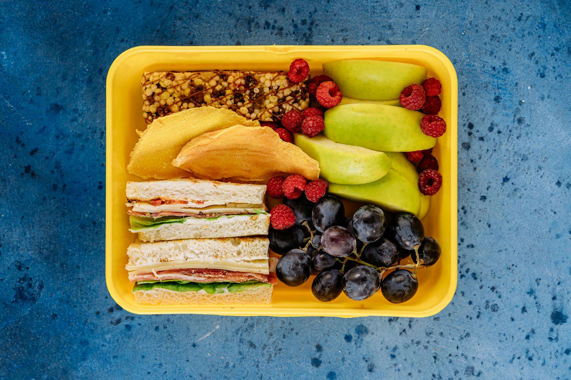 https://www.pexels.com/photo/lunch-box-with-fruit-and-sandwiches-5852324/