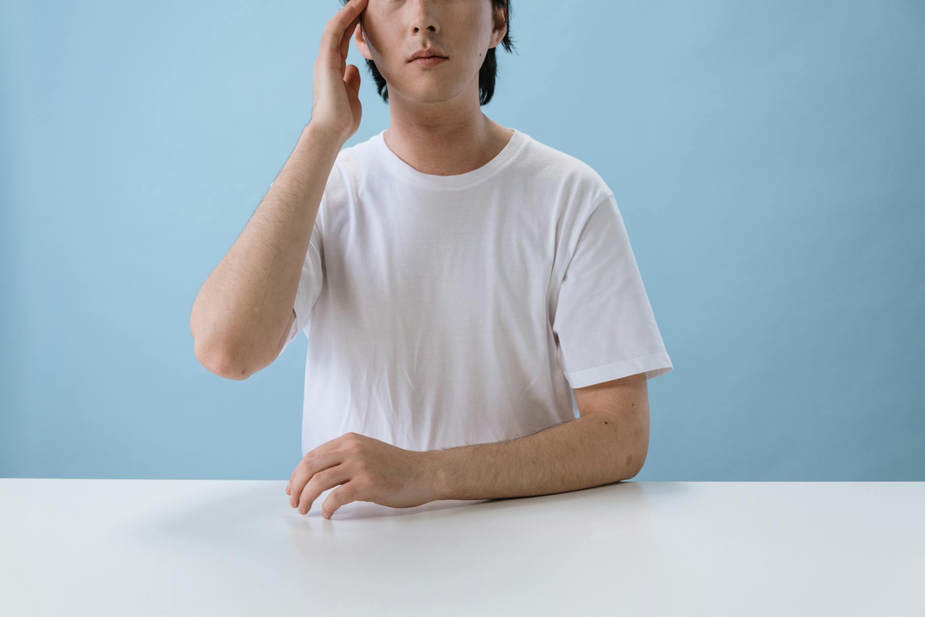 https://www.pexels.com/photo/man-in-white-t-shirt-sitting-and-touching-head-5712672/